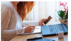 person working at her desk in a notebook and smartphone